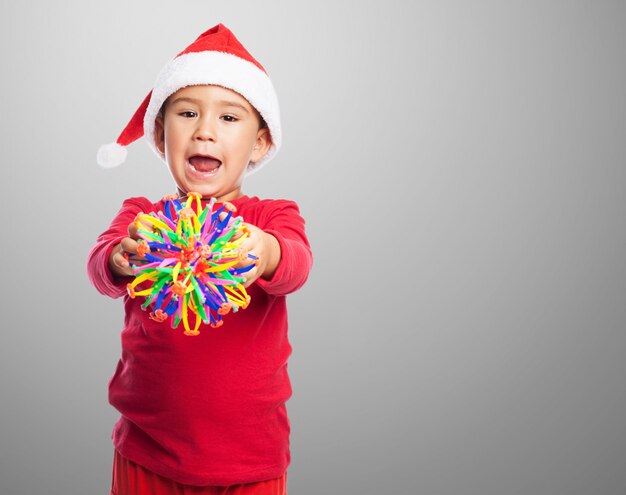 Enfant avec un jouet et un chapeau de père noël