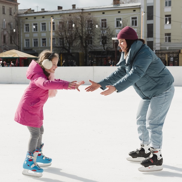 Enfant et maman patiner sur glace en plein air