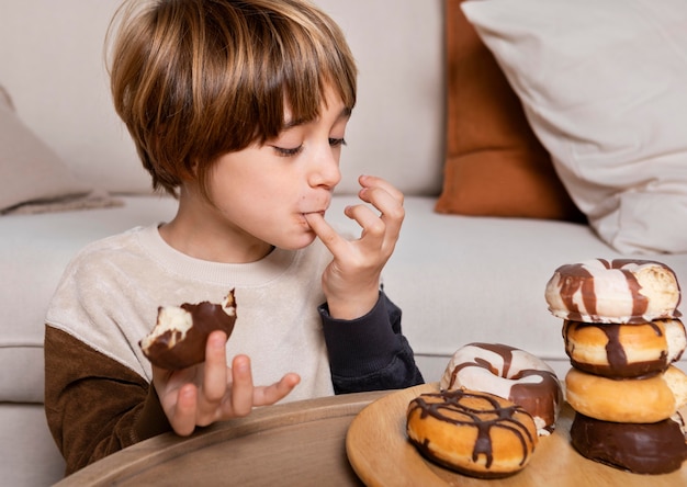 Photo gratuite enfant mangeant des beignets à la maison