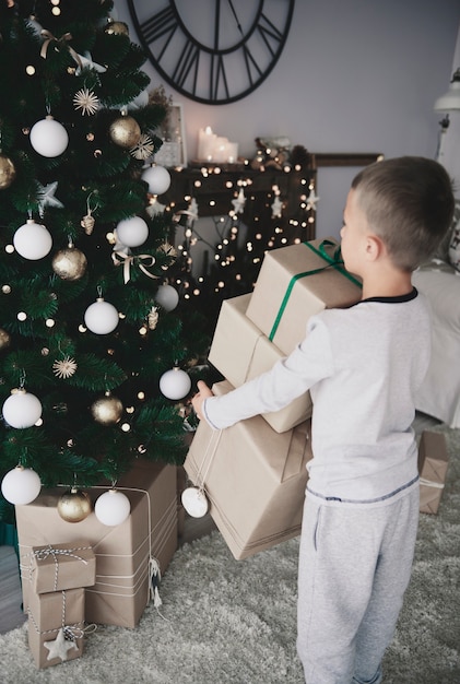 Enfant Mettant Des Cadeaux Sous Un Arbre De Noël