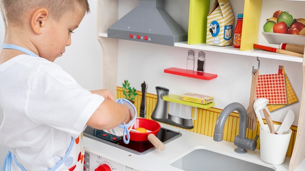 Photo gratuite enfant mignon jouant avec un jeu de cuisine