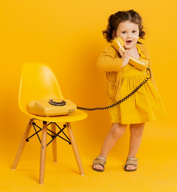 Enfant mignon posant tout en tenant le téléphone