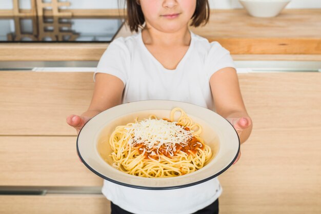 Enfant montrant une assiette avec des pâtes