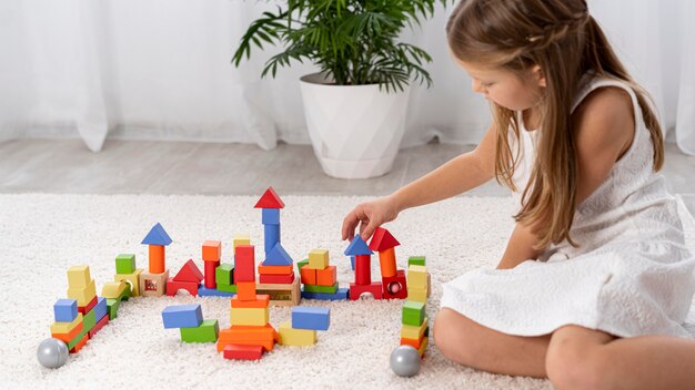 Enfant non binaire jouant avec un jeu coloré à la maison