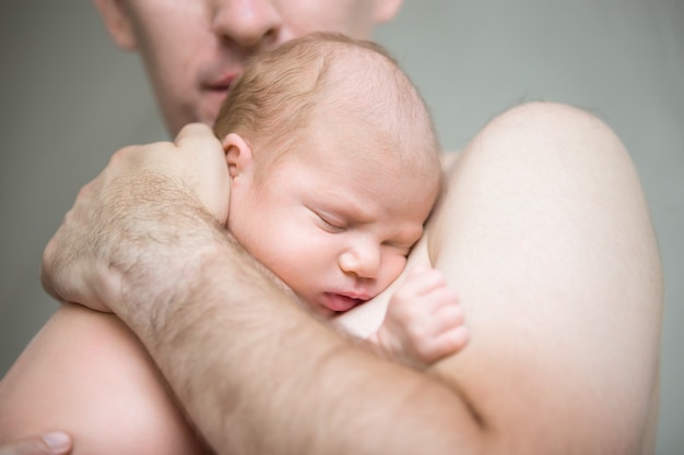 Enfant nouveau-née qui dort dans les bras mâles