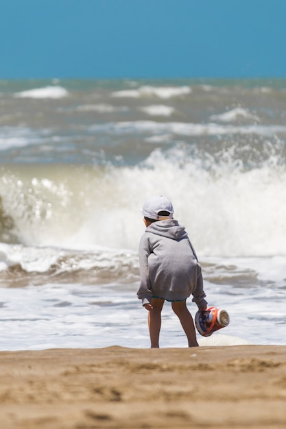 Photo gratuite enfant avec panier sur le bord de la mer près de l'eau