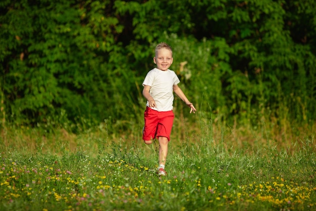 Enfant, petit garçon courant sur le pré au soleil d'été