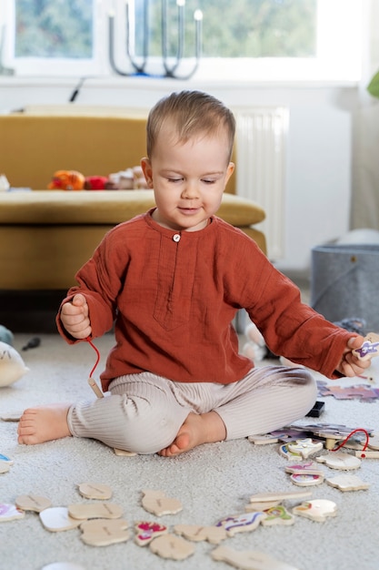 Photo gratuite enfant plein coup avec des jouets en bois sur le sol