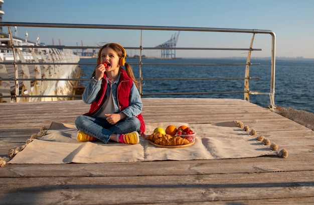 Photo gratuite enfant plein coup avec de la nourriture sur une jetée