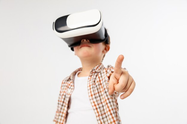 Enfant pointant vers l'avant avec des lunettes de réalité virtuelle isolés