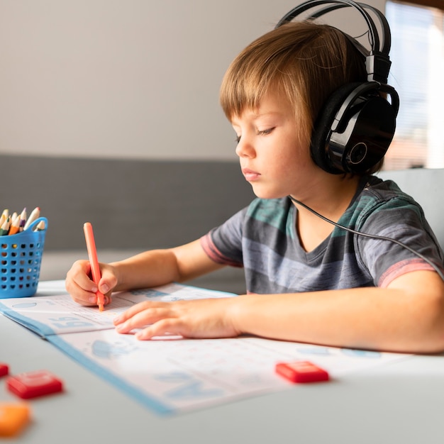 Enfant portant des écouteurs assistant à des cours virtuels