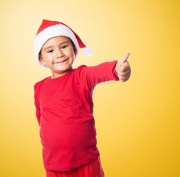 Enfant avec le pouce et le chapeau de père noël