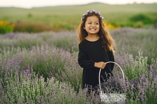 Enfant de Provence reposant dans un champ de lavande. Petite dame en robe noire. Fille avec sac.