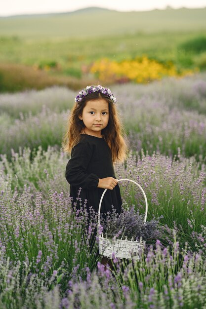 Enfant de Provence reposant dans un champ de lavande. Petite dame en robe noire. Fille avec sac.