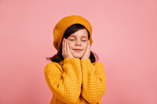 Enfant rêveur posant les yeux fermés. enfant insouciant isolé sur mur rose.