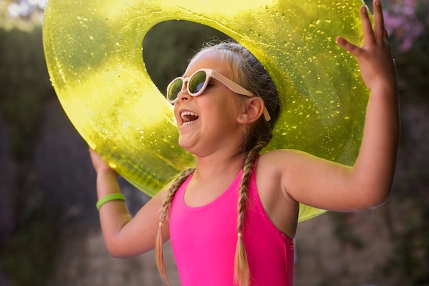 Photo gratuite enfant s'amusant avec flotteur au bord de la piscine