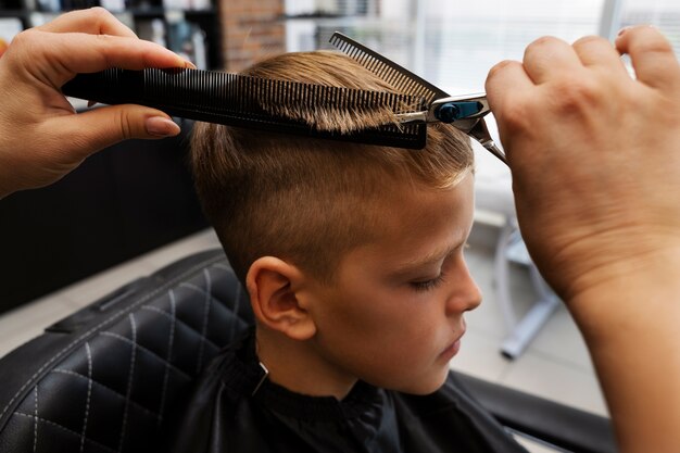Enfant se coupe les cheveux au salon high angle