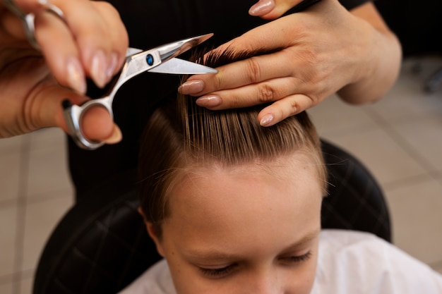 Photo gratuite enfant se coupe les cheveux au salon high angle