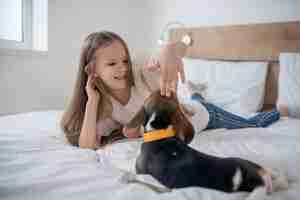 Photo gratuite enfant de sexe féminin souriant tapotant le beagle sur la tête