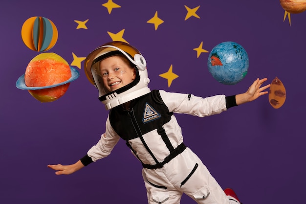 Photo gratuite enfant souriant à coup moyen portant une combinaison spatiale