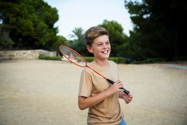 Photo gratuite enfant souriant à coup moyen avec raquette