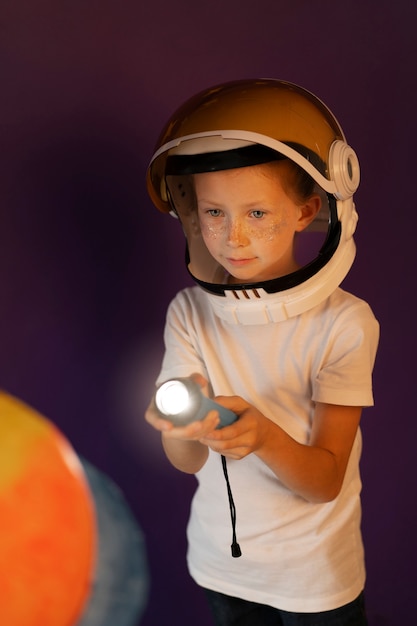 Photo gratuite enfant souriant à coup moyen tenant une lampe de poche