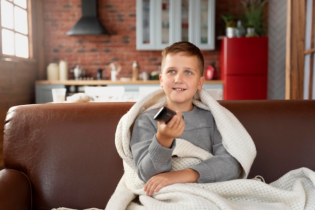 Enfant souriant de plan moyen assis sur un canapé