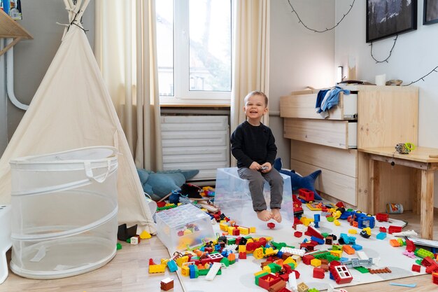 Enfant souriant plein coup assis sur un conteneur