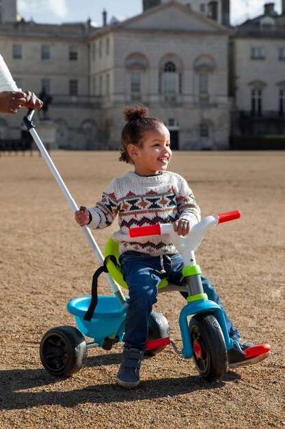 Enfant souriant plein coup assis sur un tricycle