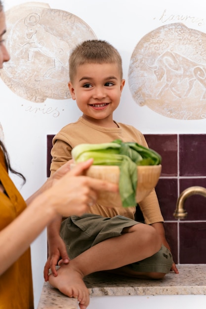 Photo gratuite enfant souriant plein coup dans la cuisine