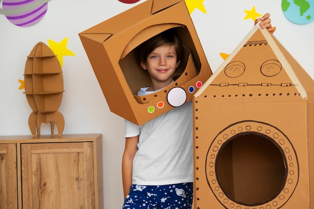 Photo gratuite enfant souriant avec vue de face de fusée en carton