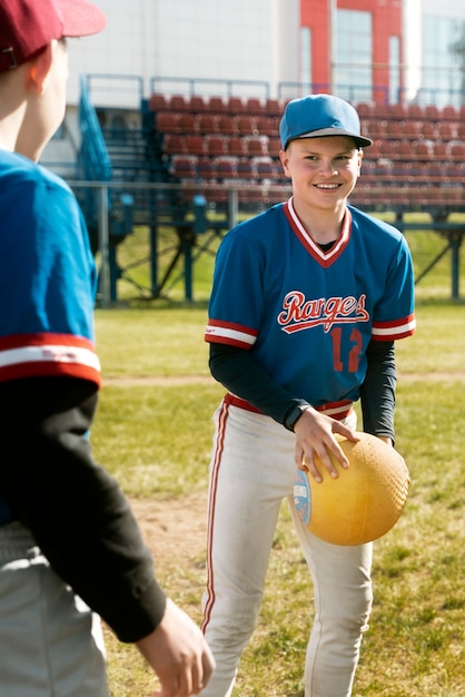 Enfant souriant vue de face tenant une balle jaune