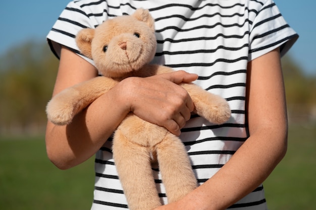 Photo gratuite un enfant tenant un ours en peluche à l'extérieur