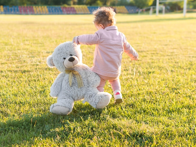 Photo gratuite enfant en vêtements roses et son jouet amical