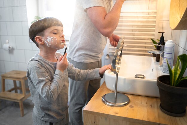 Enfant vue de côté apprenant à se raser avec un miroir