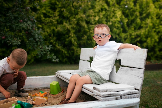 Photo gratuite enfant vue de côté assis sur un banc