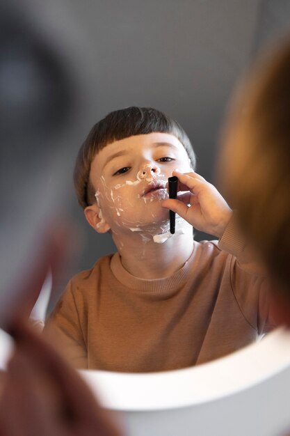 Enfant vue de face apprenant à se raser dans un miroir