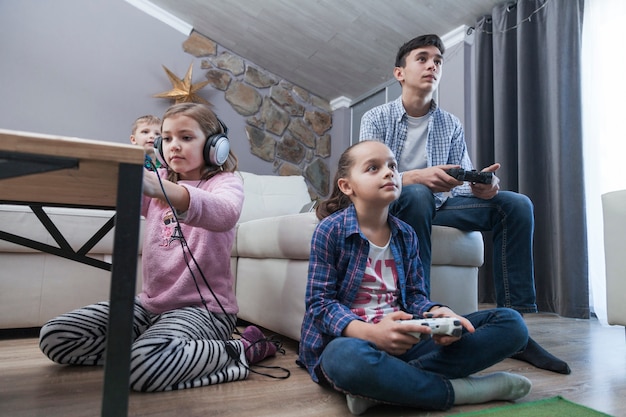 Enfants et adolescents jouant à des jeux vidéo dans le salon