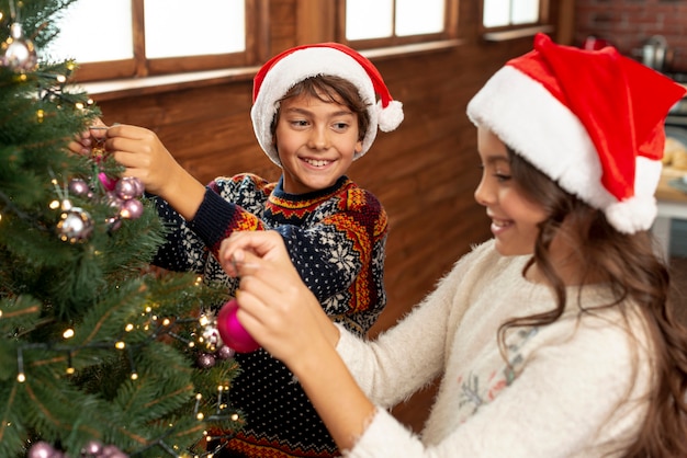 Enfants à angle élevé décorant le sapin de Noël