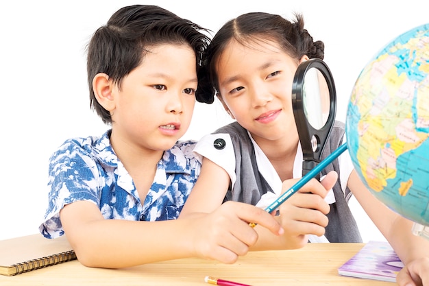 Enfants asiatiques étudient le globe à l&#39;aide de la loupe sur fond blanc