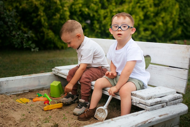 Photo gratuite enfants assis à l'extérieur vue latérale