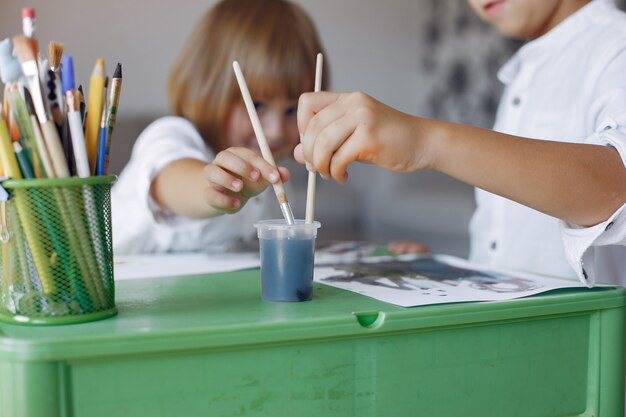 Enfants assis à la table verte et dessinant