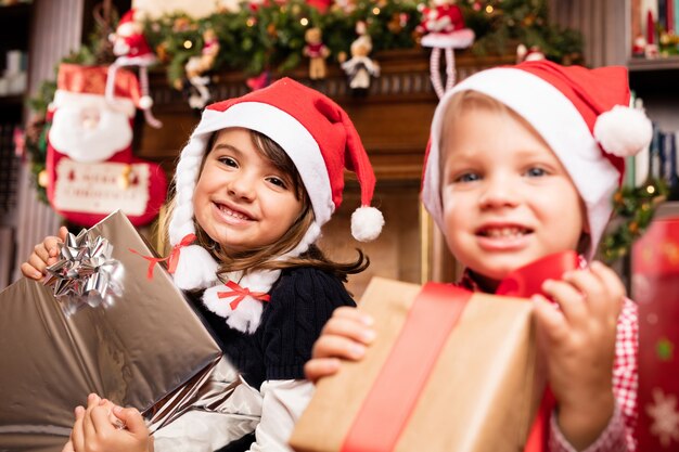 Les enfants avec des cadeaux et des chapeaux de Père Noël