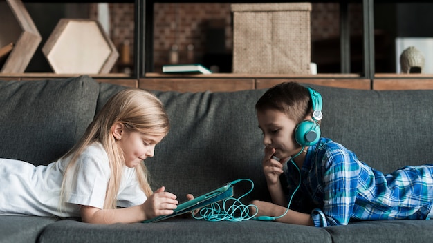 Photo gratuite enfants sur le canapé avec tablette