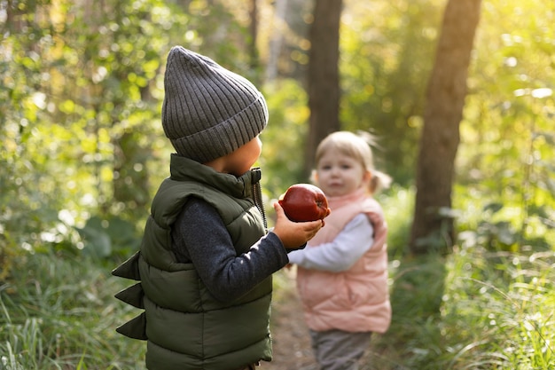 Enfants de coup moyen avec pomme dans la nature