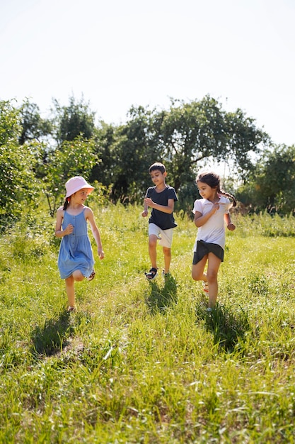 Photo gratuite enfants courant et jouant dans le champ d'herbe à l'extérieur