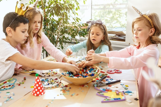 Les enfants et les décorations d'anniversaire. Les garçons et les filles à table avec de la nourriture, des gâteaux, des boissons et des gadgets de fête.