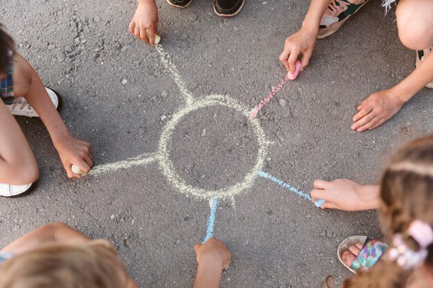 Enfants dessiner un soleil avec de la craie