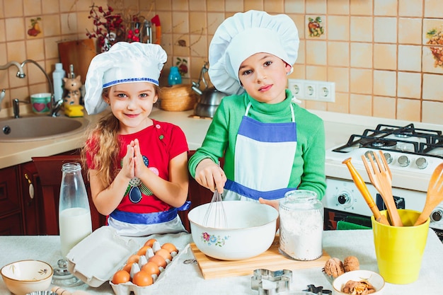 Les enfants drôles de famille heureuse préparent la pâte, cuisent des biscuits dans la cuisine