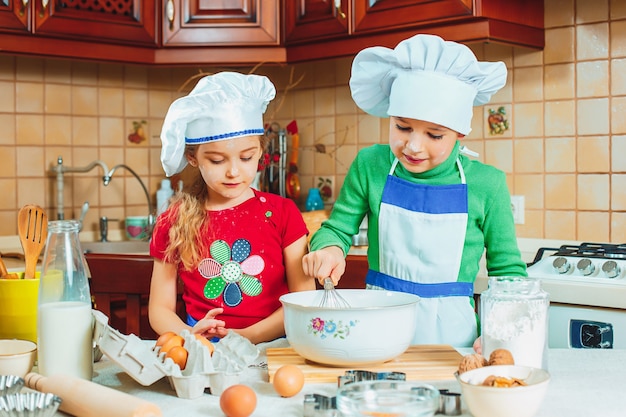 Les enfants drôles de famille heureuse préparent la pâte, cuisent des biscuits dans la cuisine